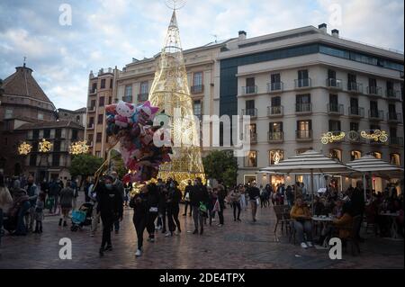 Malaga, Spanien. November 2020. Menschen, die Gesichtsmasken tragen, können auf dem Platz Plaza de la Constitucion inmitten der Coronavirus-Pandemie spazieren gehen.die andalusische Regierung sagt, dass die Region die Kurve der zweiten Welle geschlagen hat. Um die Ausbreitung der Coronavirus-Krankheit zu verhindern, wird Andalusien bis zum 10. Dezember die Fortführung der obligatorischen Beschränkungen beibehalten. Kredit: SOPA Images Limited/Alamy Live Nachrichten Stockfoto