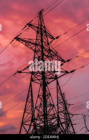 Elektrischer Turm (Strompylon) auf hellem Donner Sonnenuntergang Himmel. Hochspannung. Hohe Struktur. Stockfoto