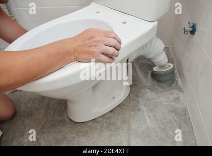 Reparaturman installiert Toilettenspülung, Toilettenschüssel im Badezimmer. Stockfoto