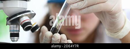 Frau im Labor schaut auf Erde mit Sprossen Stockfoto