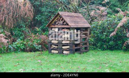 Holzlager mit Holzdach auf Gras mit Bäumen dahinter Stockfoto