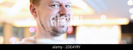 Lächelnder Mann, der im Café mit einer großen Tasse Kaffee sitzt Stockfoto