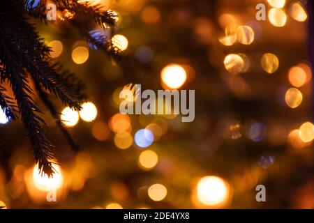 Abstrakter Hintergrund gelbe Bokeh Lichter und Zweige eines Baumes im Winter, Weihnachtshintergrund, gemütliche und warme Gefühle Stockfoto