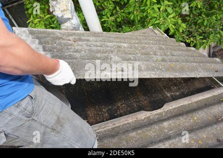 Ein Dachdecker, Dachdecker entfernt alte Asbest Dachziegel. Stockfoto