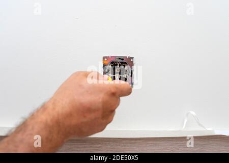 Einbau des Wandlichtschalters mit einem Schraubendreher, Nahaufnahme durch Elektriker Stockfoto
