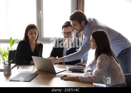 Fähiger männlicher Mentor, der der Gruppe von Praktikanten Projektdetails erklärt Stockfoto