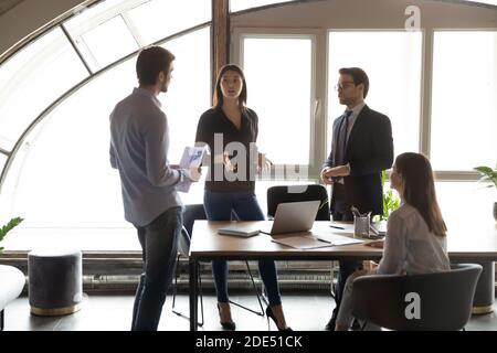 Konzentrierte, tausendjährige, multiethnische Teamkollegen, die beim Briefing ihre Ideen zum Thema Fähigkeiten austauschen Stockfoto