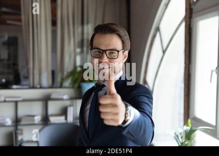 Junge Angestellte, die mit Daumen nach oben zeigen und eine Karriere im Unternehmen empfehlen Stockfoto