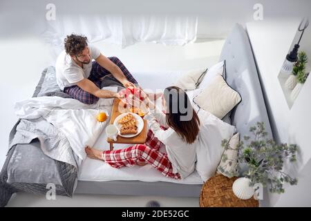 Draufsicht auf eine Frau, die von einem Kaukasianer ein Geschenk erhält Mann beim Frühstück im Bett Stockfoto