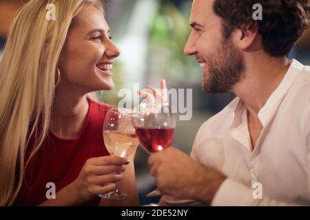 Schöne junge kaukasische Paar in der Liebe, feiern, Toasting mit Wein, einander suchen, lächeln. Stockfoto