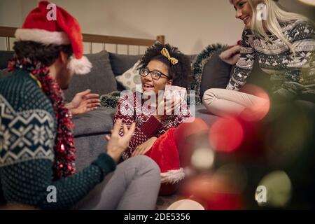 Versammelten multiethnischen Freunde auf weihnachten Austausch von Geschenken Stockfoto