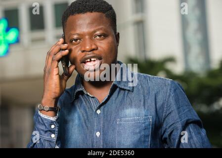 Junger afrikanischer Mann in Jeans stehend lachend kommunizierend. Stockfoto