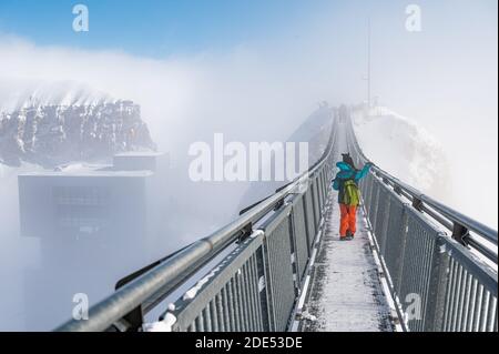 Rückansicht eines kleinen Mädchens, das mit Schnee auf der Spitze des Berges spielt. Urlaub mit Kindern nach Alps im Winter. Glacier 3000, les Diablerets, Schweizla Stockfoto