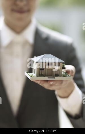 Geschäftsmann hält Modellhaus. Architektur, Bau, Bau, Immobilien und Immobilienkonzept Stockfoto