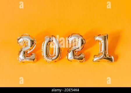 2021 Air Gold Folie Ballons Zahlen mit Kopieplatz auf orangefarbenem Hintergrund. Minimales Neujahrs- und Weihnachtsfeiertagskonzept. Stockfoto