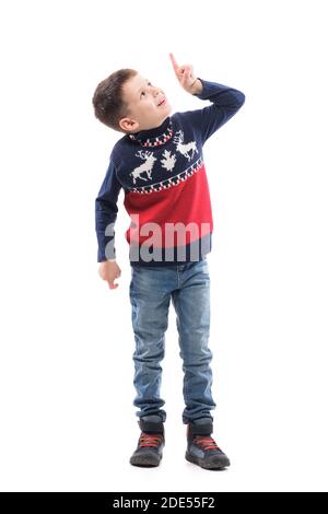 Glücklich aufgeregt junge Kind in Weihnachten Pullover mit Virtual Reality Touchscreen zeigt Finger nach oben. Ganzkörper-Porträt isoliert auf weißem Hintergrund. Stockfoto