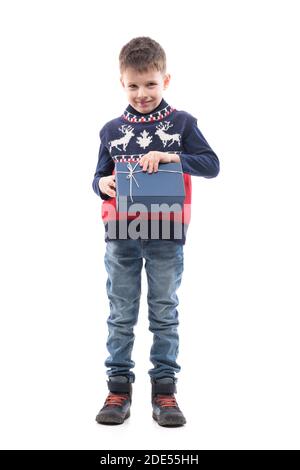 Glücklich hoffnungsvoll kleiner Junge Eröffnung Geschenkbox in Weihnachten Pullover schaut in die Kamera. Ganzkörper-Porträt isoliert auf weißem Hintergrund. Stockfoto