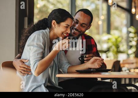 Lächelndes Paar, das romantische Gespräche bei einem Kaffee in einem Café führt. Mann und Frau, die Kaffee trinken und in einem Café lächeln. Stockfoto