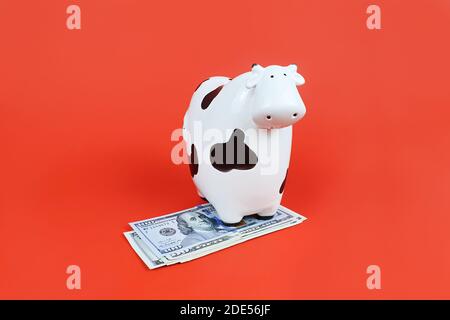 2021 Neujahr Symbol Kuh und Dollar Scheine auf rotem Hintergrund. Gefleckte weiße und schwarze Geldbox Kuh. Stockfoto