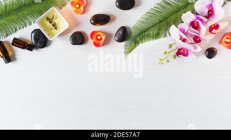 Bio-Spa-Hautpflegeprodukte mit ätherischem Öl und Spa-Massagesteinen Draufsicht auf weißem Holzhintergrund. Spa-Behandlung Hintergrund. Stockfoto