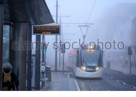 Edinburgh, Schottland, Großbritannien. November 2020. Dichter Morgennebel im Stadtzentrum, die Straßenbahn, die sich hier der Straßenbahnhaltestelle in der Princes Street nähert. Straßen extrem ruhig wegen der Covid-19 Coronavirus Sperrmaßnahmen. Kredit: Craig Brown/Alamy Live Nachrichten Stockfoto