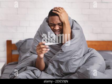 Krank Schwarz Mann Mit Fieber Sitzen Im Bett Zu Hause Stockfoto