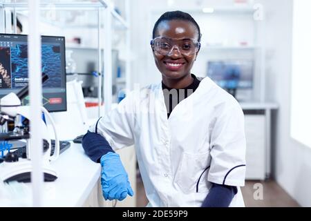 Portrait eines professionellen afrikanischen Wissenschaftlers, der im sterilen Labor vor der Kamera lächelt. Multiethnisches Team von Forschern, die in mikrobiologischen Labortests für medizinische Zwecke arbeiten. Stockfoto