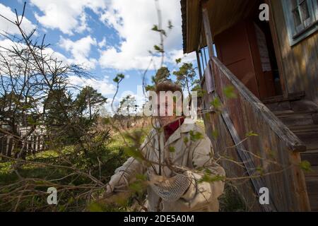 Eine alte Frau in der Nähe des Hauses auf ihrem Bauernhof im Dorf. Stockfoto