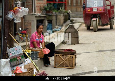 ZHAOXING DONG, CHINA - Juni 21, 2012: Chinesische Miao-minorität Frau verkaufen frische Himbeeren Obst in der Straße. Stockfoto