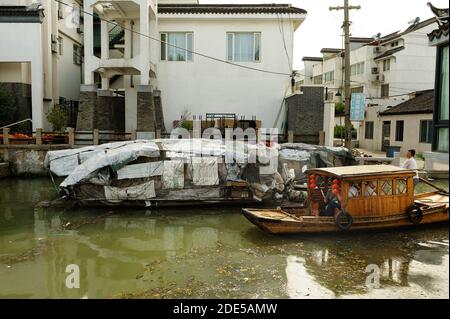 SUZHOU, CHINA - 25. JULI 2010: Touristen Boot vor grungy Lastkähne in schwimmende Häuser & verschmutztes Wasser verwandelt. Suzhou, "Venedig der e Stockfoto