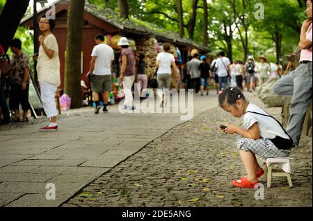 SUZHOU, CHINA - 25. JULI 2010: Kleines Mädchen souvenir Hersteller spielen mit Smartphone in Suzhou, das Venedig des Ostens, die beliebteste Wasser schleppen Stockfoto