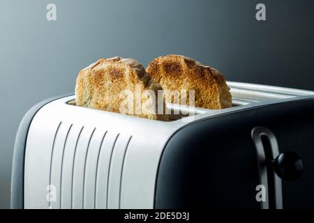 Frisch getoastetes Brot tauchte in einem modernen Toaster auf. Das Brot wird gebräunt und geröstet, bereit zum Frühstück gegessen werden Stockfoto