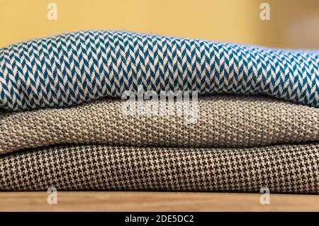 Eine Nahaufnahme von drei bunten Pullovern, die gefaltet und aufgestapelt sind Übereinander auf einem Holztisch Stockfoto