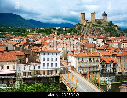 Ariège Fluss und Schloss im Dorf Foix, Midi-Pyrénées, Pyrenäen, Departement Ariege, Frankreich, Europa. Häuser mit roten Ziegeldächern. Stockfoto