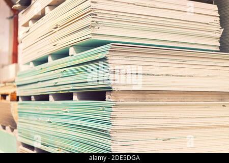 Palette mit Trockenwandplatten Gipskarton im Lagerhaus des Gebäudes. Stapeln von weißen Gipskartonplatten, Trockenbau oder Gipskarton. Gipskartonplatten Stockfoto
