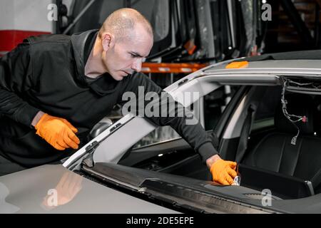 Nahaufnahme, Autoverglasung, Befestigung und Reparatur einer Windschutzscheibe. Frontscheibe ersetzen Prozess eines Autos in einer Garage Service. Reinigen eines Armaturenbretts. Hochwertige Fotos Stockfoto