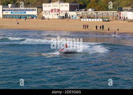 Bournemouth, Dorset, Großbritannien. November 2020. Wetter in Großbritannien: Die Strände sind voll, da die Menschen an der Küste für ihre Bewegung und frische Luft und die Sonne an einem schönen warmen sonnigen Tag an Bournemouth Strände während des letzten Wochenende der Lockdown 2 genießen. Bournemouth und Dorset werden dann in Tier2. Jetskifahrer tun akrobatische Tricks Trick. Jet Skifahrer Jetskifahrer Jetskifahrer Jetskifahrer Jetskifahrer Jetskifahrer Jetskifahrer Jetskifahren Jetskifahren Jetskifahren. Quelle: Carolyn Jenkins/Alamy Live News Stockfoto