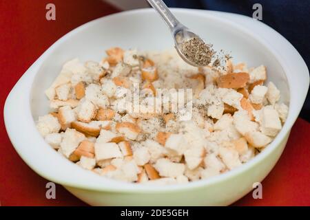 Getrocknete Brotwürfel werden gewürzt, um ein Dressing Auflauf zu werden Stockfoto