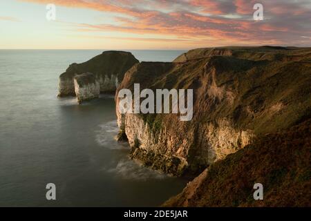 Sonnenaufgang über dem Meer und erodierte Klippen unter hellem Himmel bei Ebbe entlang der Nordostküste entlang Flamborough Head in East Riding of Yorshire, Großbritannien. Stockfoto