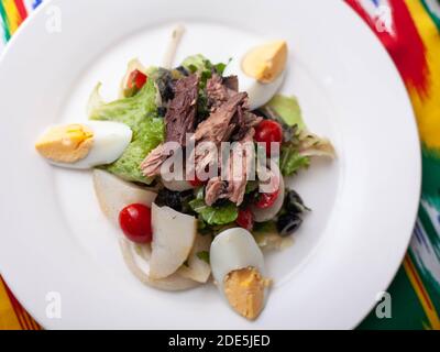 Salat mit Thunfisch. Salat mit Eiern, Kräutern, Zwiebeln, Kirschtomaten und Thunfisch. Asiatischer Stil Stockfoto