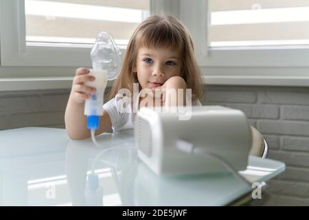 Nettes kleines Mädchen hält einen Vernebler Maske in den Händen. Behandlung von Bronchitis und Asthma mit Inhalation Stockfoto