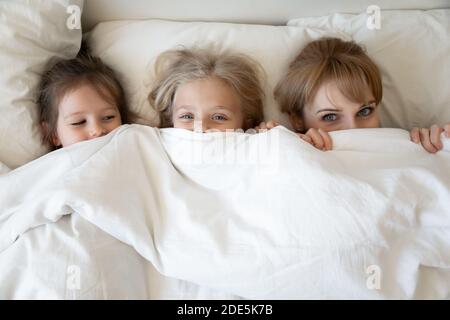 Draufsicht Mutter und zwei entzückende Töchter gucken aus Decke Stockfoto