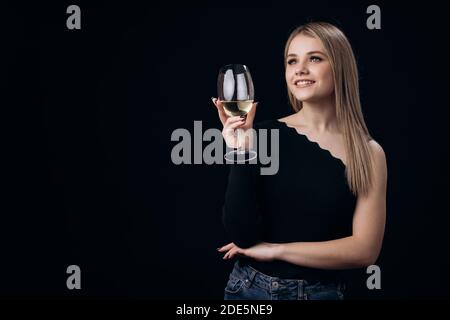 Verträumte blonde hält ein Glas Weißwein Stockfoto