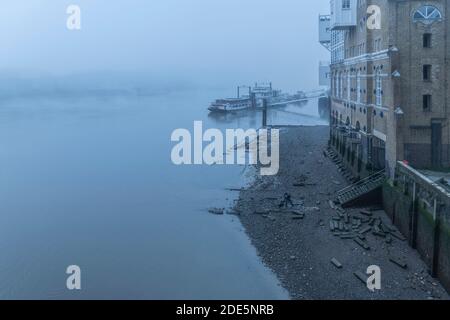 Butlers Wharf Pier bei Ebbe mit einem Strand an der Themse bei dichtem nebligen und nebligen launischen Wetter im Londoner Stadtzentrum während der Covid-19 Coronavirus-Sperre, England, Großbritannien Stockfoto