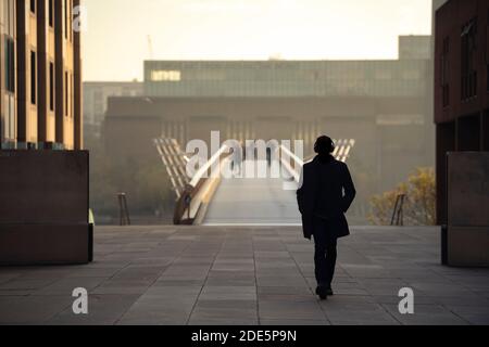 Menschen, die bei Sonnenuntergang über die Millennium Bridge gehen, mit der Tate Modern Gallery in London, aufgenommen in England während der Coronavirus Covid-19 Sperre, Großbritannien, Europa Stockfoto