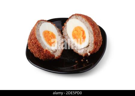 Scotch Ei in der Mitte auf schwarzem Porzellan untertasse schließen geschnitten Nach oben Stockfoto