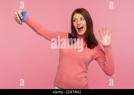 Positive Brünette Frau blogger sagen Hallo an alle ihre Abonnenten Aufnahme Video-Nachricht auf Smartphone, Popularität in sozialen Netzwerken. innenstudi Stockfoto