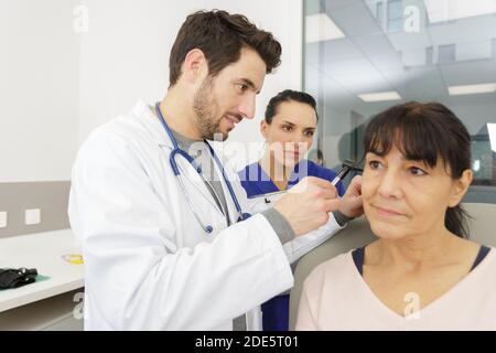 hno-Arzt schaut mit einem Instrument in das Ohr des Patienten Stockfoto