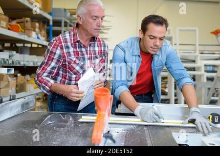 Männer messen aus Metallstange in der Werkstatt Stockfoto