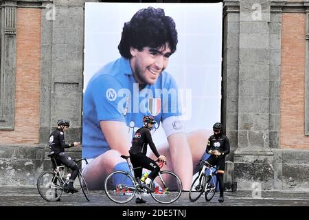 Neapel, Italien. November 2020. Drei Radfahrer machen ein Foto des riesigen Plakats zu Ehren von Diego Armando Maradona in Piazza Plebiscito platziert. Italien, 29. November 2020. (Foto von Vincenzo Izzo/Sipa USA) Quelle: SIPA USA/Alamy Live News Stockfoto